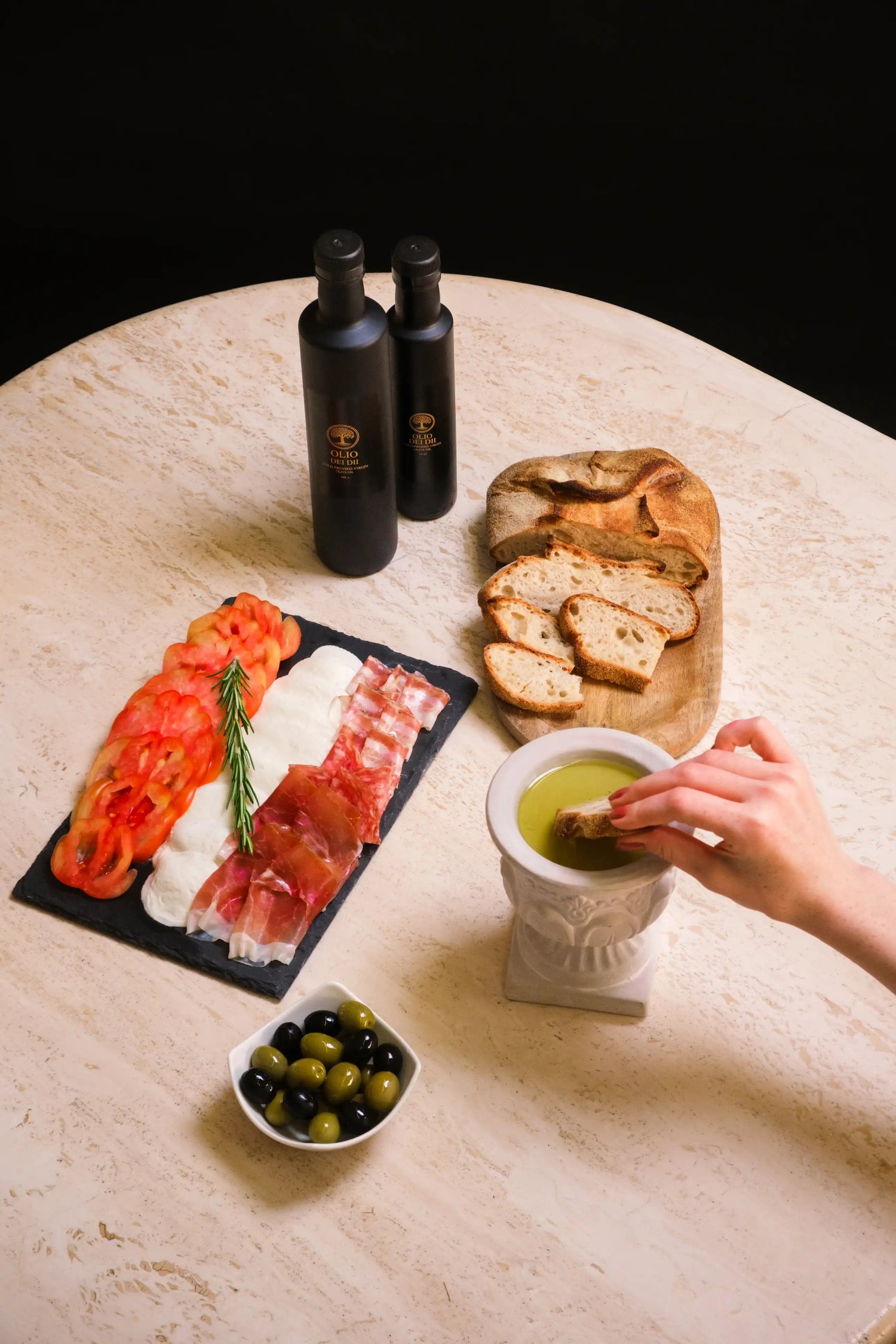 Premium Olivenöl aus Kalabrien auf Marmortisch mit Brot und gemischter Platte serviert